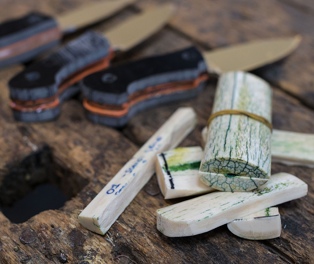 Stainless steel blades and handles made from giraffe bone on a wooden work bench