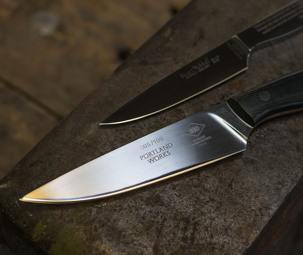Two artisan knives made from stainless steel, the Portland Works logo visible on the blade