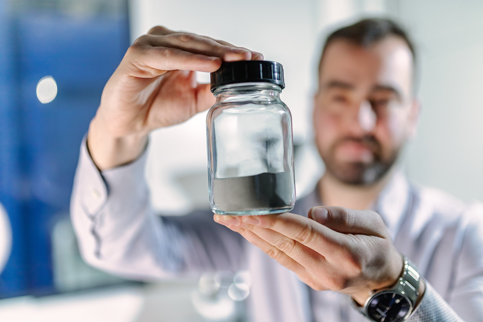 A man holding a jar of stailess steel powder.